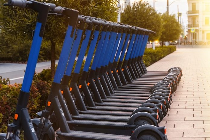 Electric scooters in row on the parking lot. Public kick scooters on the street